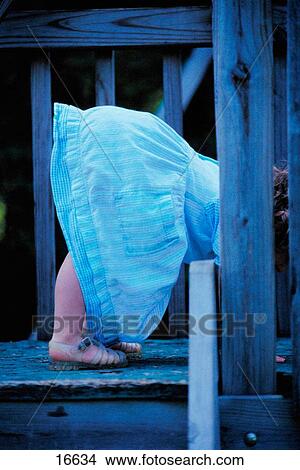 Picture - Little girl in blue denim dress bending over. Fotosearch