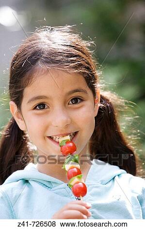 Little girl is eating a healthy snack View Large Photo Image Stock Photo - Little girl is eating a healthy snack. Fotosearch