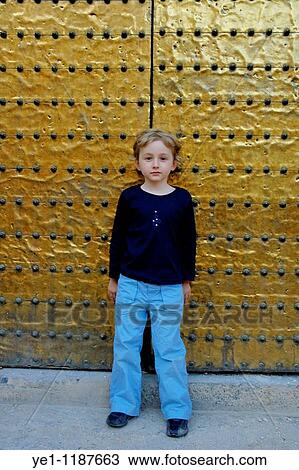 Stock Image - Little girl leaning against a bronze door belonging to the Catedral de Cordoba, a former medieval mosque in Cordoba, Andalusia, Spain.. Fotosearch