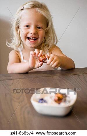 Picture - Little girl peeling a bonbon. Fotosearch
