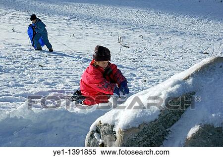 Little girl playing in snow by herself while her brother goes sledding View Large Photo Image Stock Photography - Little girl playing in snow by herself while her brother goes sledding. Fotosearch