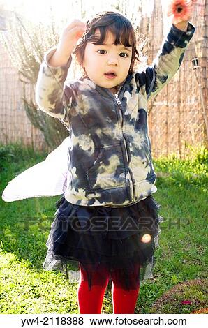 Stock Photo - Little girl playing with a flower in the back garden.. Fotosearch
