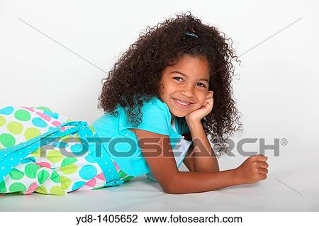 Little Girl posing lying down looking at the camera smailing View Large Photo Image Stock Image - Little Girl posing lying down looking at the camera smailing. Fotosearch