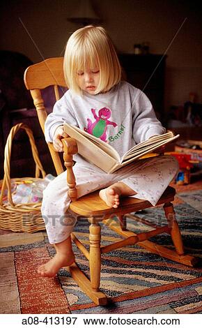 Little girl reads storybook in rocking chair. View Large Photo Image Stock Photo - Little girl reads storybook in rocking chair.. Fotosearch