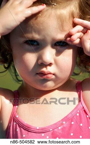 Stock Image - Little girl shielding eyes from sun. Fotosearch
