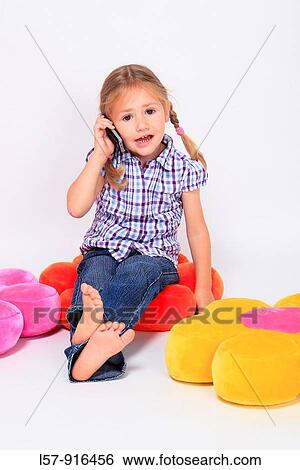 Stock Photograph - little girl sitting on cushion with mobile phone, Switzerland. Fotosearch