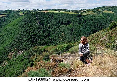 Picture - little girl sitting on the edge of the La Truyere River gorges, Cantal department, Auvergne region, France, Europe. Fotosearch