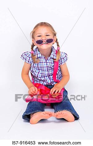 Stock Image - little girl sitting with handbag over shoulder wearing sunglases, Switzerland. Fotosearch