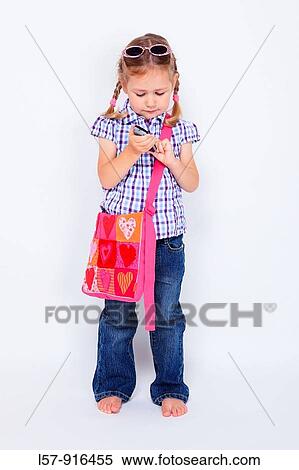 Stock Photography - little girl standing with mobile phone and handbag over shoulder wearing sunglases, Switzerland. Fotosearch