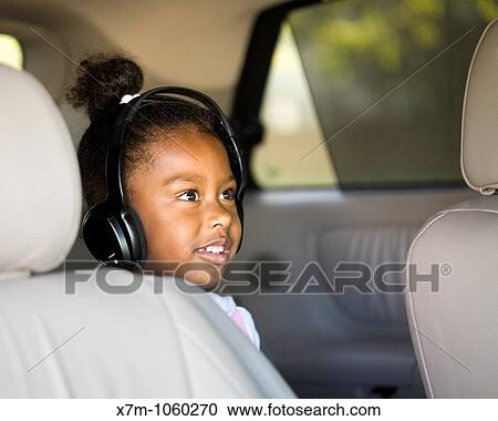 Little girl watches a DVD in the minivan with headphones View Large Photo Image Stock Image - Little girl watches a DVD in the minivan with headphones. Fotosearch