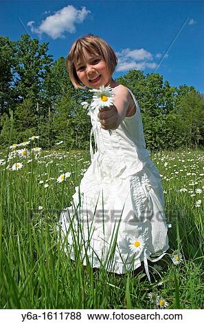 Little girl wearing white dress standing in field holding daisies smiling portrait View Large Photo Image Stock Photo - Little girl wearing white dress standing in field holding daisies smiling portrait. Fotosearch