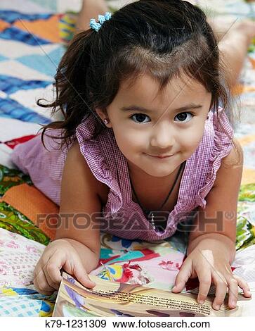 LIttle girl with book looking at camera and smiling. View Large Photo Image Stock Photo - LIttle girl with book looking at camera and smiling.. Fotosearch