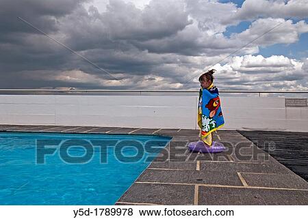 Stock Photo - little girl wrapped in towel next to swimming pool under heavy storm clouds, Geneva, Switzerland, end of August. Fotosearch