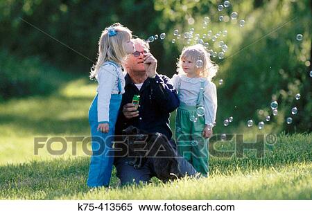 Little girls blowing bubbles with their grandfather View Large Photo Image Stock Photography - Little girls blowing bubbles with their grandfather. Fotosearch