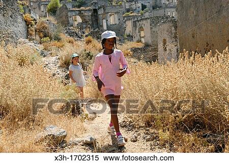 Stock Photography - little girls in Kayakoy which was a Greek speaking village, it was abandonned after a population exchange agreement was signed by the Turkish and Greek governments in 1923, Turkey, Eurasia. Fotosearch
