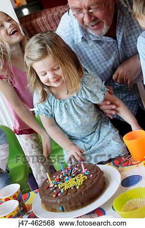 Little girl's third birthday party, looking at her cake with her grandad. View Large Photo Image Stock Photo - Little girl's third birthday party, looking at her cake with her grandad.. Fotosearch