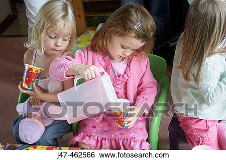 Stock Photograph - Little girl's third birthday party, two girl pouring themselves a drink.. Fotosearch