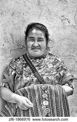 Stock Photograph - Local colorful woman against bright wall with local print dress portrait in tourist village of Antigua Guatemala. Fotosearch