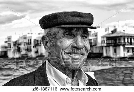 Local man with Greek hat scene in downtown near beach with famous Little Venice in background in Mykonos in the Greek Islands in Greece Europe View Large Photo Image Stock Photograph - Local man with Greek hat scene in downtown near beach with famous Little Venice in background in Mykonos in the Greek Islands in Greece Europe. Fotosearch