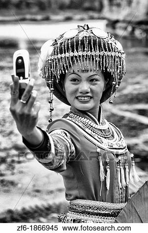 Local woman in traditional costume taking camera cell phone portrait in Guilin Yangshuo area of China View Large Photo Image Stock Photography - Local woman in traditional costume taking camera cell phone portrait in Guilin Yangshuo area of China. Fotosearch