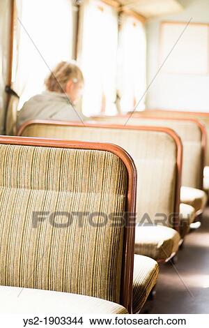 Lonely elderly female sitting alone in a train, out of focus View Large Photo Image Picture - Lonely elderly female sitting alone in a train, out of focus. Fotosearch