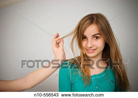 Stock Image - Long blond-hair teen girl interacting with the hand and arm of another teen girl.. Fotosearch