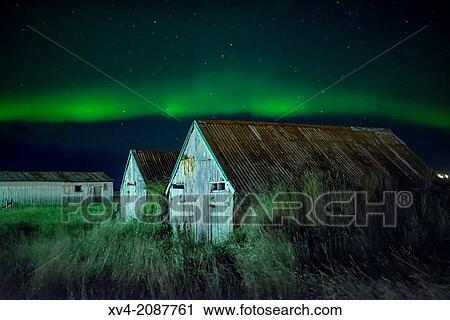 Stock Image - Long exposure with houses foreground and northern lights. Iceland.. Fotosearch