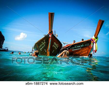 Longtail boat and tourists in snorkel on Phi Phi Le island Krabi province, Andaman Sea, Thailand View Large Photo Image Picture - Longtail boat and tourists in snorkel on Phi Phi Le island Krabi province, Andaman Sea, Thailand. Fotosearch