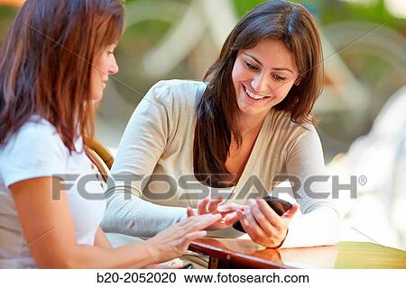 Looking a smartphone. Women sisters 35 and 40 years taking coffee on a terrace. Donostia. San Sebastian. Gipuzkoa. Basque Country- Spain. View Large Photo Image Stock Image - Looking a smartphone. Women sisters 35 and 40 years taking coffee on a terrace. Donostia. San Sebastian. Gipuzkoa. Basque Country- Spain.. Fotosearch