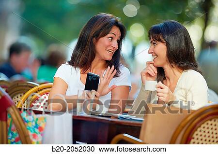 Looking a smartphone. Women sisters 35 and 40 years taking coffee on a terrace. Donostia. San Sebastian. Gipuzkoa. Basque Country- Spain. View Large Photo Image Stock Image - Looking a smartphone. Women sisters 35 and 40 years taking coffee on a terrace. Donostia. San Sebastian. Gipuzkoa. Basque Country- Spain.. Fotosearch