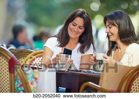 Looking a smartphone. Women sisters 35 and 40 years taking coffee on a terrace. Donostia. San Sebastian. Gipuzkoa. Basque Country- Spain. View Large Photo Image Stock Image - Looking a smartphone. Women sisters 35 and 40 years taking coffee on a terrace. Donostia. San Sebastian. Gipuzkoa. Basque Country- Spain.. Fotosearch