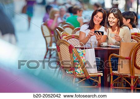 Looking a smartphone. Women sisters 35 and 40 years taking coffee on a terrace. Donostia. San Sebastian. Gipuzkoa. Basque Country- Spain. View Large Photo Image Stock Image - Looking a smartphone. Women sisters 35 and 40 years taking coffee on a terrace. Donostia. San Sebastian. Gipuzkoa. Basque Country- Spain.. Fotosearch