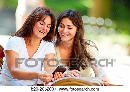 Looking a smartphone. Women sisters 35 and 40 years taking coffee on a terrace. Donostia. San Sebastian. Gipuzkoa. Basque Country- Spain. View Large Photo Image Stock Photo - Looking a smartphone. Women sisters 35 and 40 years taking coffee on a terrace. Donostia. San Sebastian. Gipuzkoa. Basque Country- Spain.. Fotosearch
