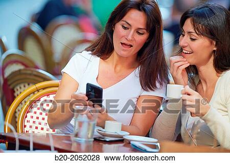 Looking a smartphone. Women sisters 35 and 40 years taking coffee on a terrace. Donostia. San Sebastian. Gipuzkoa. Basque Country- Spain. View Large Photo Image Stock Photo - Looking a smartphone. Women sisters 35 and 40 years taking coffee on a terrace. Donostia. San Sebastian. Gipuzkoa. Basque Country- Spain.. Fotosearch