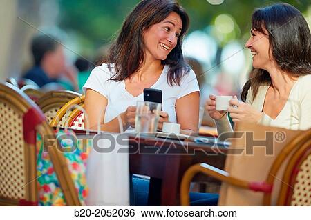 Looking a smartphone. Women sisters 35 and 40 years taking coffee on a terrace. Donostia. San Sebastian. Gipuzkoa. Basque Country- Spain. View Large Photo Image Stock Photograph - Looking a smartphone. Women sisters 35 and 40 years taking coffee on a terrace. Donostia. San Sebastian. Gipuzkoa. Basque Country- Spain.. Fotosearch