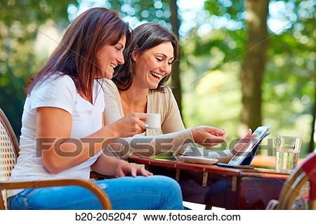 Looking a tablet. Women sisters 35 and 40 years taking coffee on a terrace. Donostia. San Sebastian. Gipuzkoa. Basque Country- Spain. View Large Photo Image Stock Photo - Looking a tablet. Women sisters 35 and 40 years taking coffee on a terrace. Donostia. San Sebastian. Gipuzkoa. Basque Country- Spain.. Fotosearch