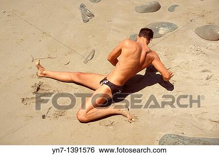 Looking down on a man doing stretching exercises on a sandy beach View Large Photo Image Stock Photograph - Looking down on a man doing stretching exercises on a sandy beach. Fotosearch