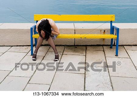 Picture - Looking down pretty woman on a Yellow bench. Fotosearch