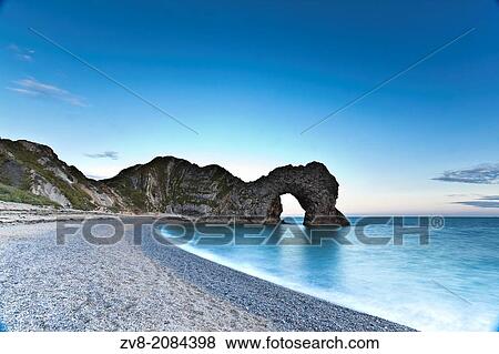 Looking towards Durdle Door from the beach. The evening light producing soft colours at the end of the day. View Large Photo Image Stock Photo - Looking towards Durdle Door from the beach. The evening light producing soft colours at the end of the day.. Fotosearch