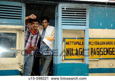 Stock Image - Loughing young indian men on board the Nilgiri Mountain Railway at Coonoor railway station in rain. India, Tamil Nadu, Coonoor 2005. Fotosearch
