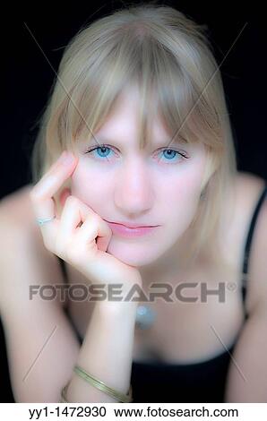 Stock Image - Low contrast studio portrait of a young, blonde woman with blue eyes.. Fotosearch