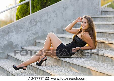 Stock Image - Lying down on a staircase smiling young woman. Fotosearch