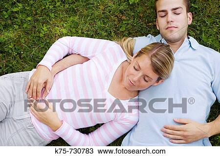 Stock Image - Lying in his arms on the lawn. Fotosearch