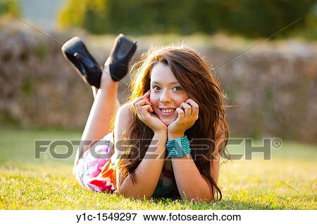 Stock Photo - Lying on a grass and smiling young teen woman. Fotosearch