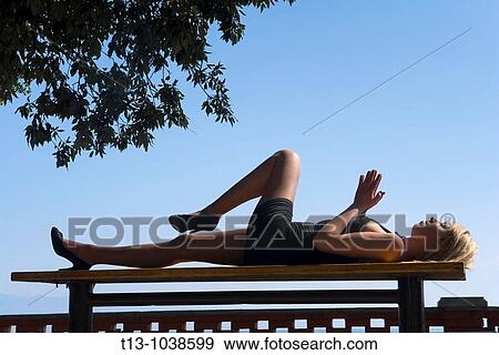 Lying on a park bench pretty woman body silhouette View Large Photo Image Stock Photo - Lying on a park bench pretty woman body silhouette. Fotosearch