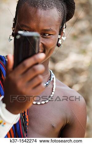 Maasai man wearing traditional dress and using modern smart phone. View Large Photo Image Picture - Maasai man wearing traditional dress and using modern smart phone.. Fotosearch