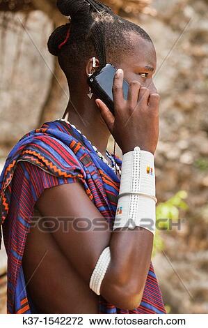 Stock Image - Maasai man wearing traditional dress and using modern smart phone.. Fotosearch
