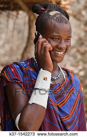 Stock Image - Maasai man wearing traditional dress and using modern smart phone.. Fotosearch