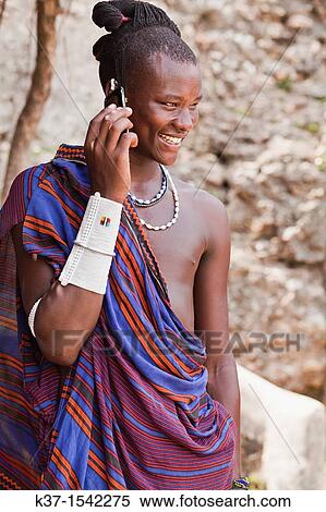 Stock Photography - Maasai man wearing traditional dress and using modern smart phone.. Fotosearch