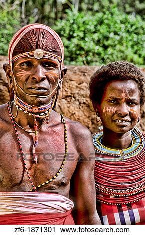 Stock Image - Maasai tribe people couple in costume traditional dress in jungles near hut near Kenya Africa. Fotosearch